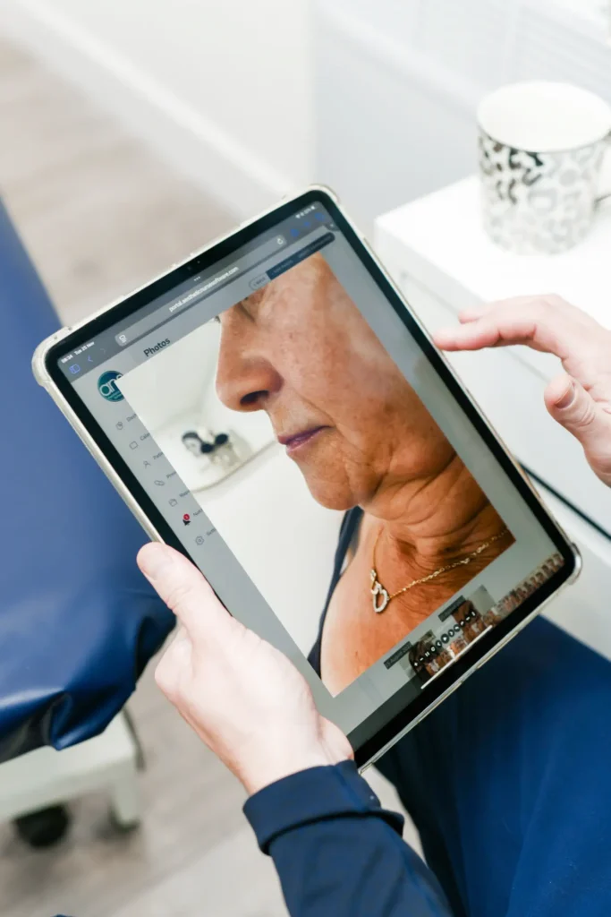 A patient looking at an ipad with an image of her face and neck